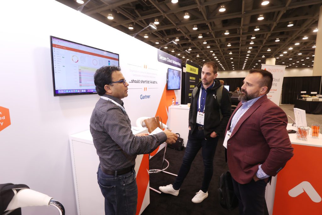 An Aviatrix rep (left) discusses the company's multicloud networking software with a pair of Cloud Wars attendees. 